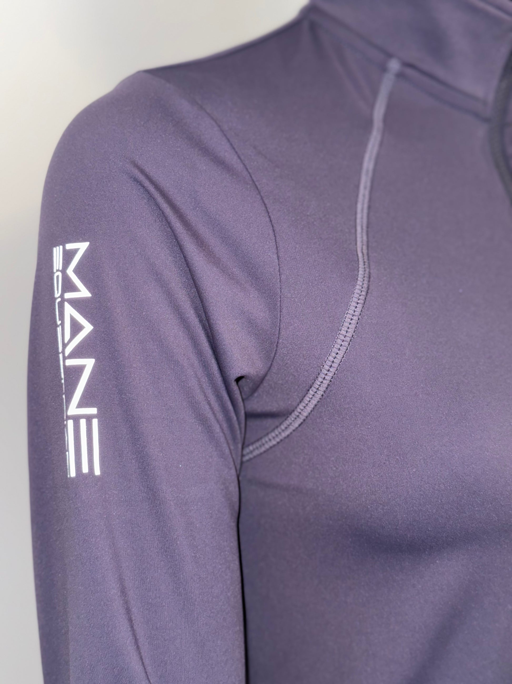 purple long-sleeve shirt with a brand logo on the sleeve against a white background showing details of the logo in a close up shot