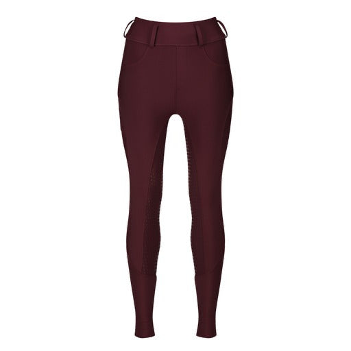 A person stood next to an apple tree wearing burgundy long sleeved performance base layer and matching riding breeches with a logo on the baselayer chest